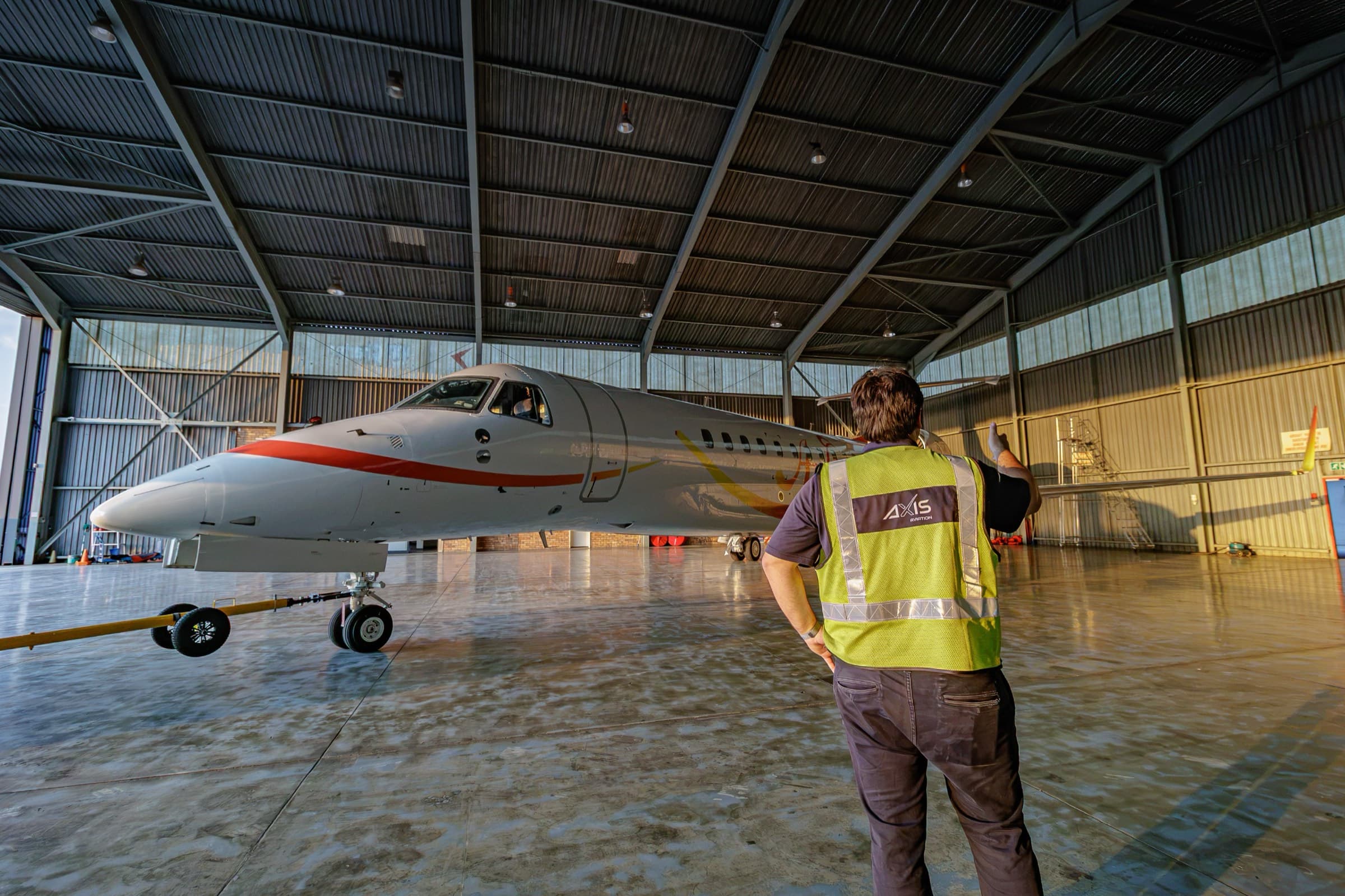 An AXIS Aviation ground crew member alongside a business jet in the hangar at Lanseria